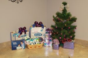 Toothbrush and toothpaste gifts beside a small Christmas tree